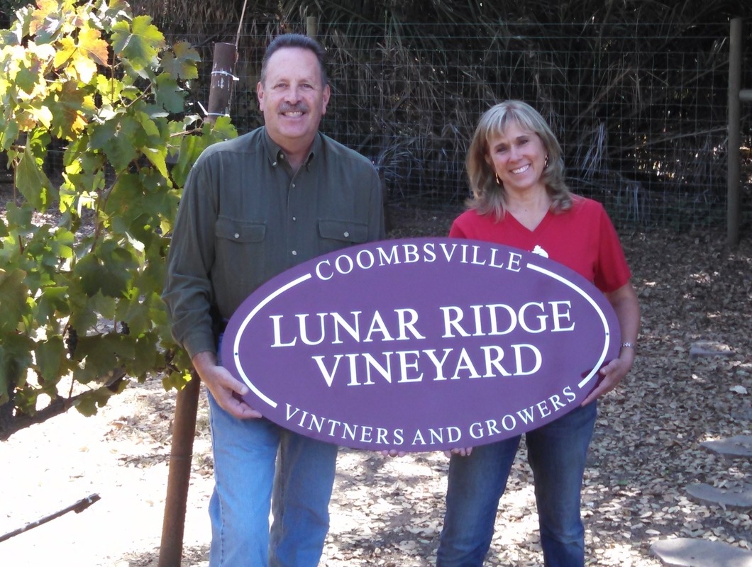 Ray and Theresa Joske holding Lunar Ridge Vineyard sign